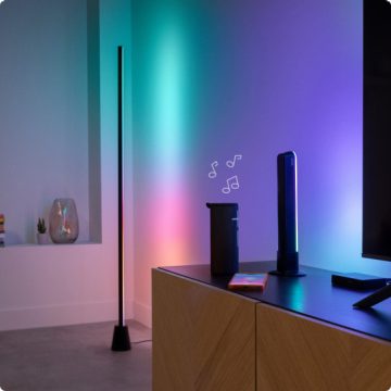 A Gradient Floor Light, Gradient Light Bar and TV Backlight, all projecting light that is synced with music playing from a speaker in a modern living room.
